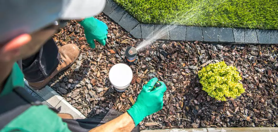 A man repairing sprinkler system in a landscape